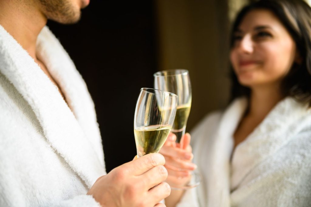 Couple saying cheers with Prosecco in spa robes