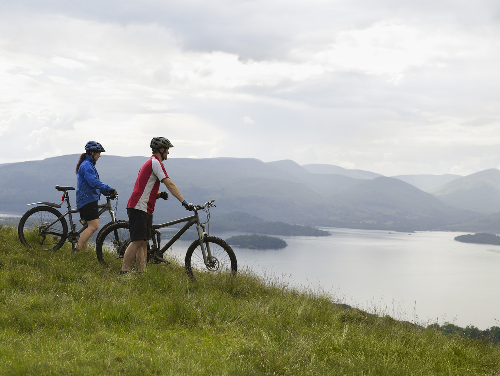 Side view of a couple with bicycles near the peaceful lake.