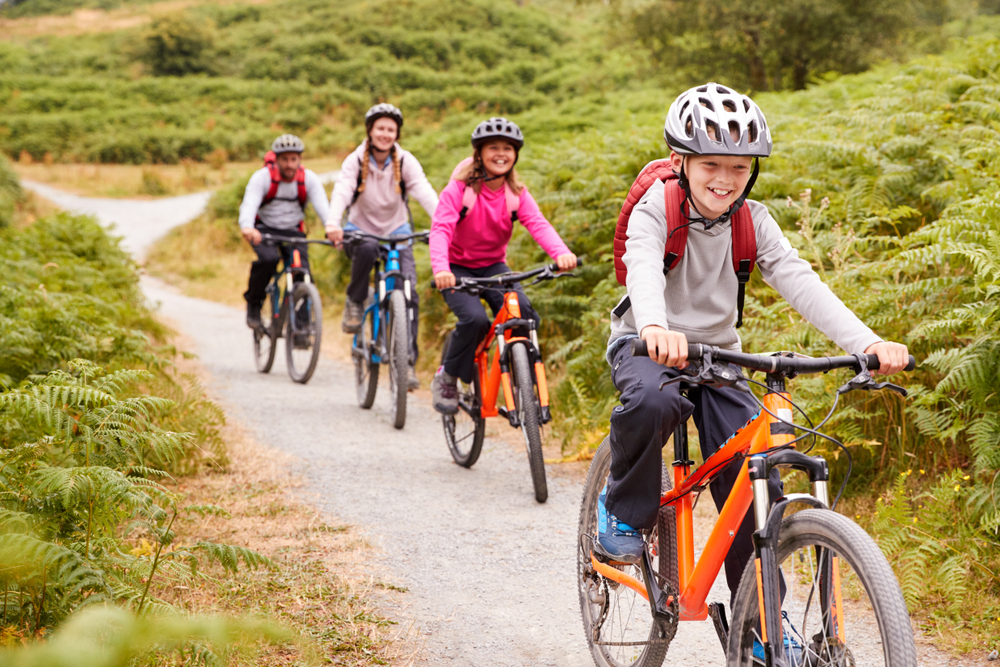 Pre-teen boy riding mountain bike with his sister and parents during a family camping trip, close up.