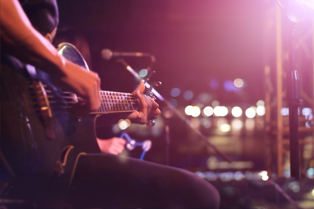 Guitarist on stage with low lighting.