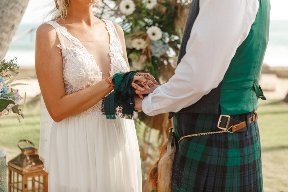 Beautiful Scottish couple groom and bride. National traditional clothing - kilt. Couple holding hands during wedding ceremony.