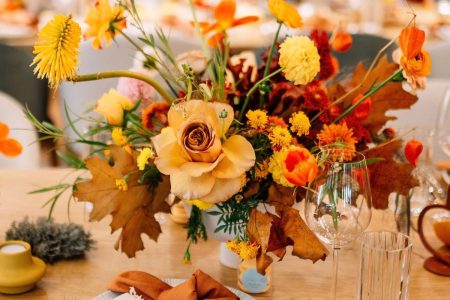 Autmn wedding table set up with flower arrangements, napkins, glasses, cutlery.