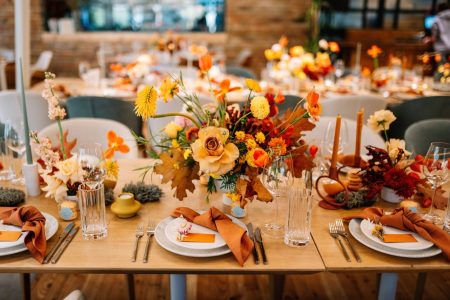 Autmn wedding table set up with flower arrangements, napkins, glasses, cutlery.