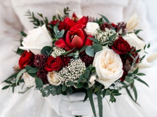Wedding bouquet of red and white roses in the hands of the bride. Winter wedding concept.