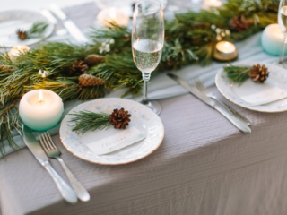 Aerial view of winter green garland on a wedding table with white plates and and blue candles.