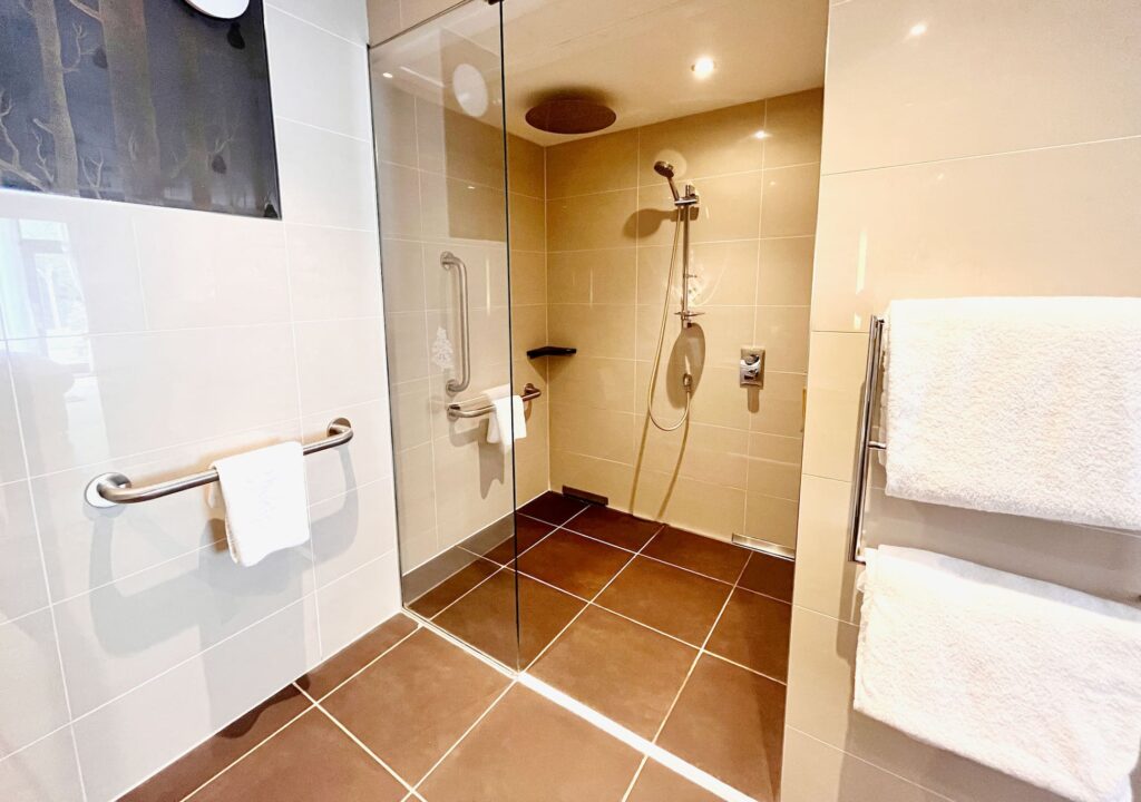 An accessible shower area in a Garden Room at Kingsmills Hotel with handrails and rain shower.