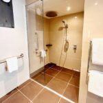 An accessible shower area in a Garden Room at Kingsmills Hotel with handrails and rain shower.