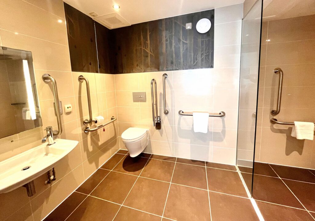 An accessible bathroom at Kingsmills with handrails, low toilet and sink.