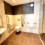 An accessible bathroom at Kingsmills with handrails, low toilet and sink.