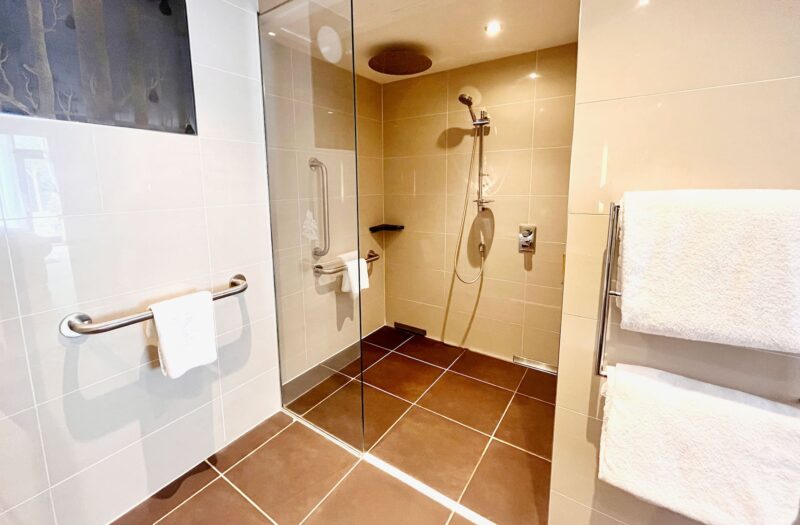 An accessible shower area in a Garden Room at Kingsmills Hotel with handrails and rain shower.