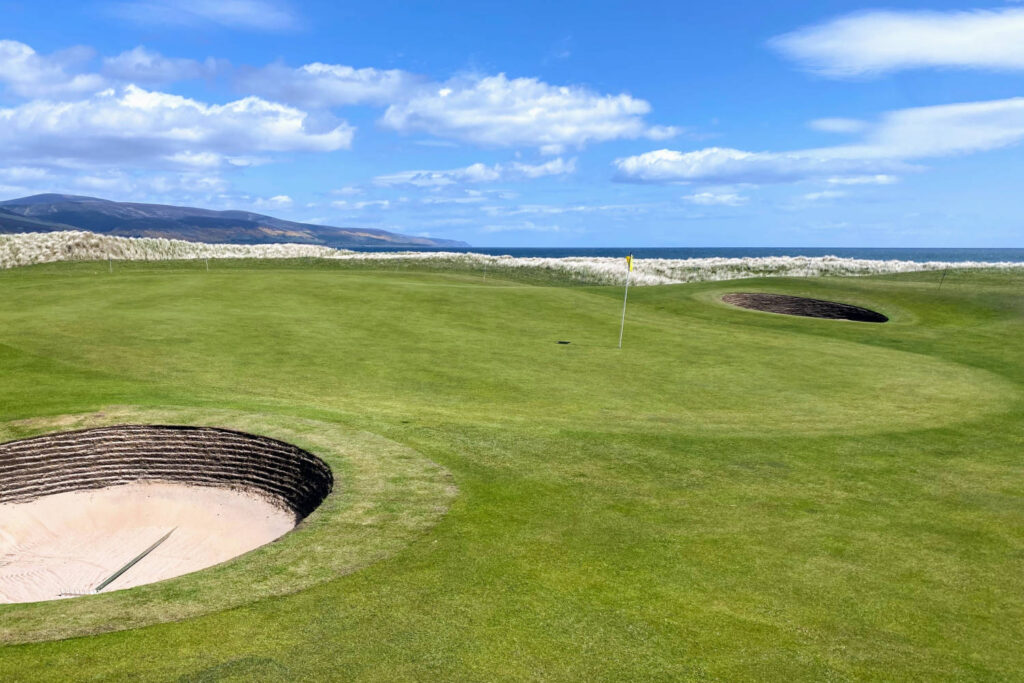 A closeup view of a green and pot bunker on a classic links style course in Brora, Scotland