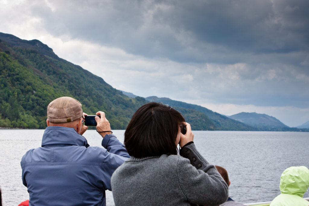 Tourists on a boat trip, taking photos of Loch Ness
